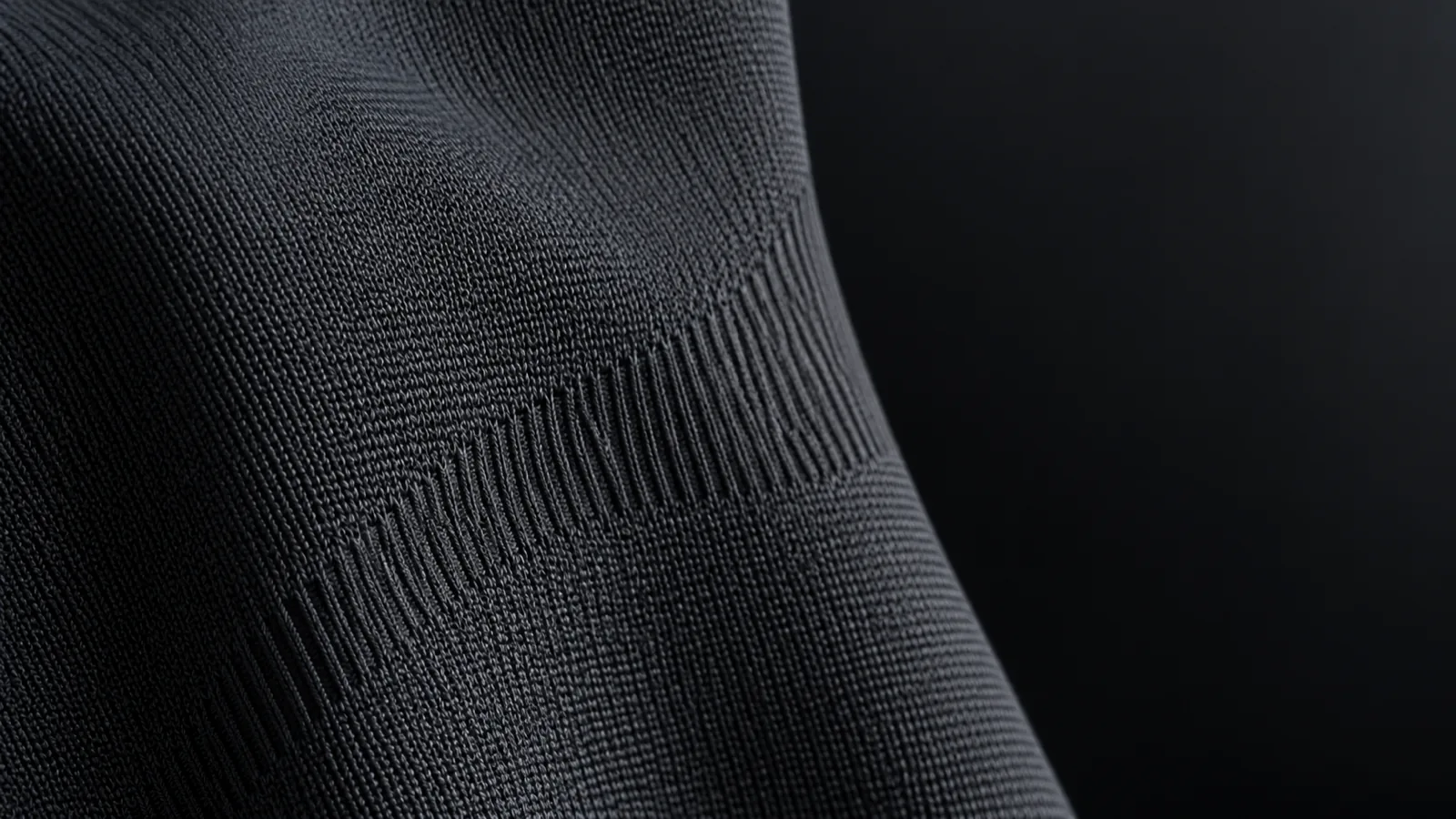 Macro of matte seamless knit fabric showing the loop structure and a rib zone transition